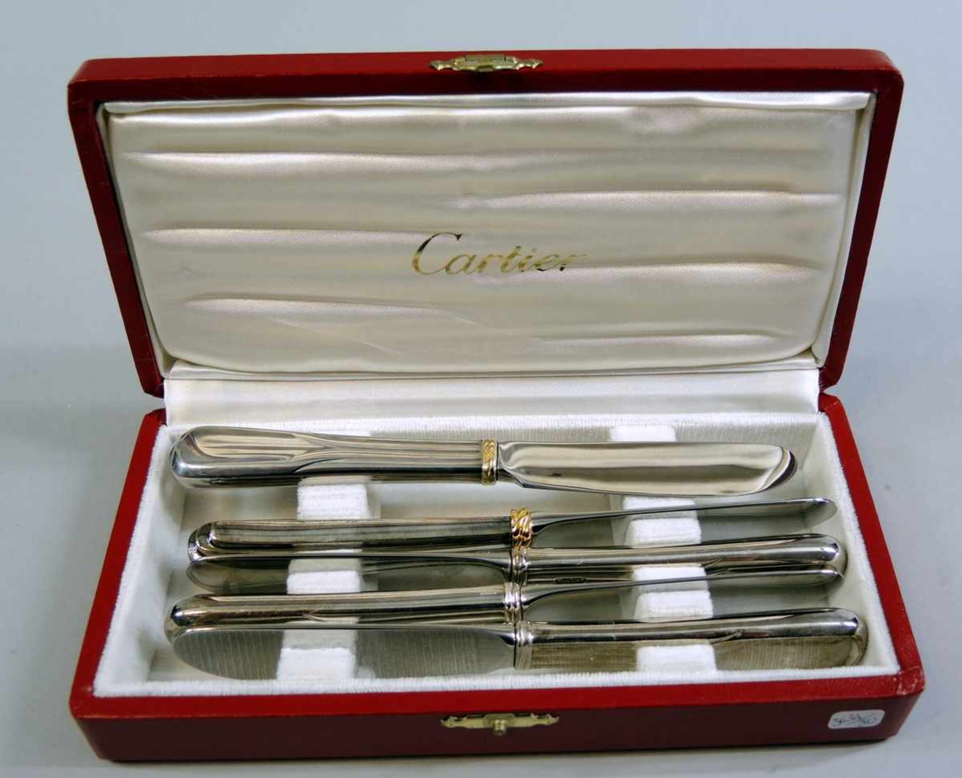 Cartier, 5 Buttermesser Stahl, Cartier signiert, vergoldet. In originaler Box. Leichte