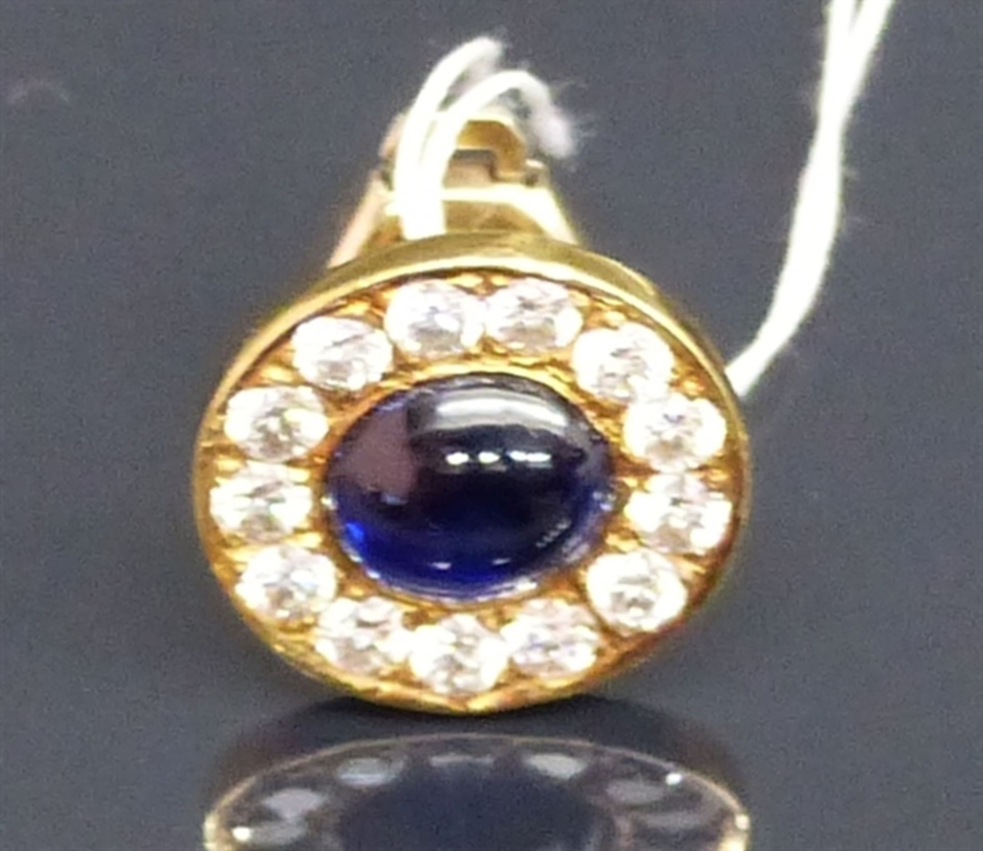 Reversknopf 18 kt. Gelbgold, 1 Saphircabochon, ca 1,07 ct, Kranz mit 13 Brillanten, zusammen ca 0,46