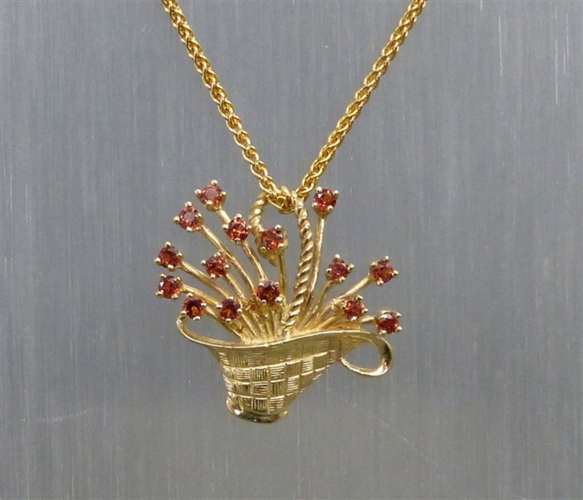 Blütenkorb als Anhänger, 14 kt. Gelbgold, 15 kl. rötliche Edelsteine, an 14 kt. Gelbgoldkette,