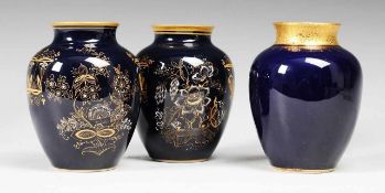 Drei Vasen Weiß, glasiert. Ovoide Formen. Kobaltblauer Fond. Goldener stilisierter Floral- u.