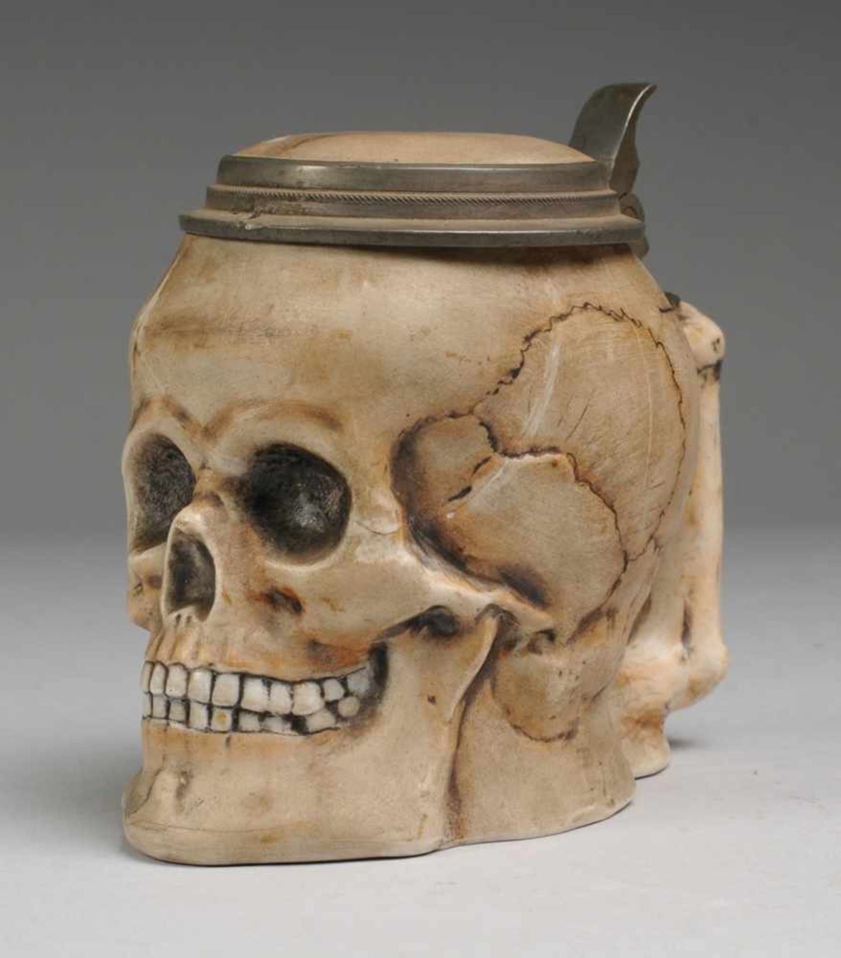 Totenkopf-Bierkrug Biskuitporzellan. Krug in Form eines Schädels mit Griff in Knochenform.