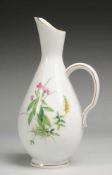 Vase mit Blumenmalerei Weiß, glasiert. Ovoider Korpus in Kannenform mit geschweiftem Henkel.