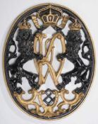 WappenmedaillonEisenguss, schwarz u. goldfarben lackiert. In ovaler Rahmung durchbrochene