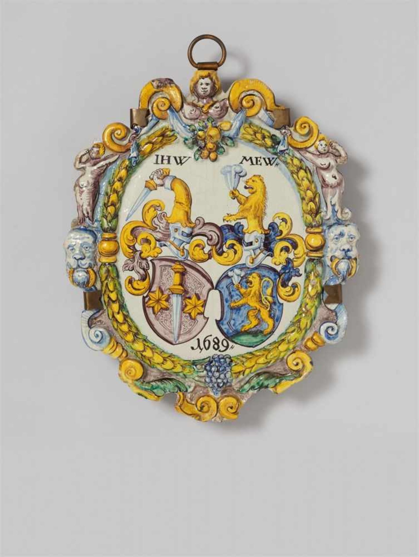 Ofenschild mit AllianzwappenFayence, polychromer Scharffeuerdekor, Metallmontierung. Reliefiert