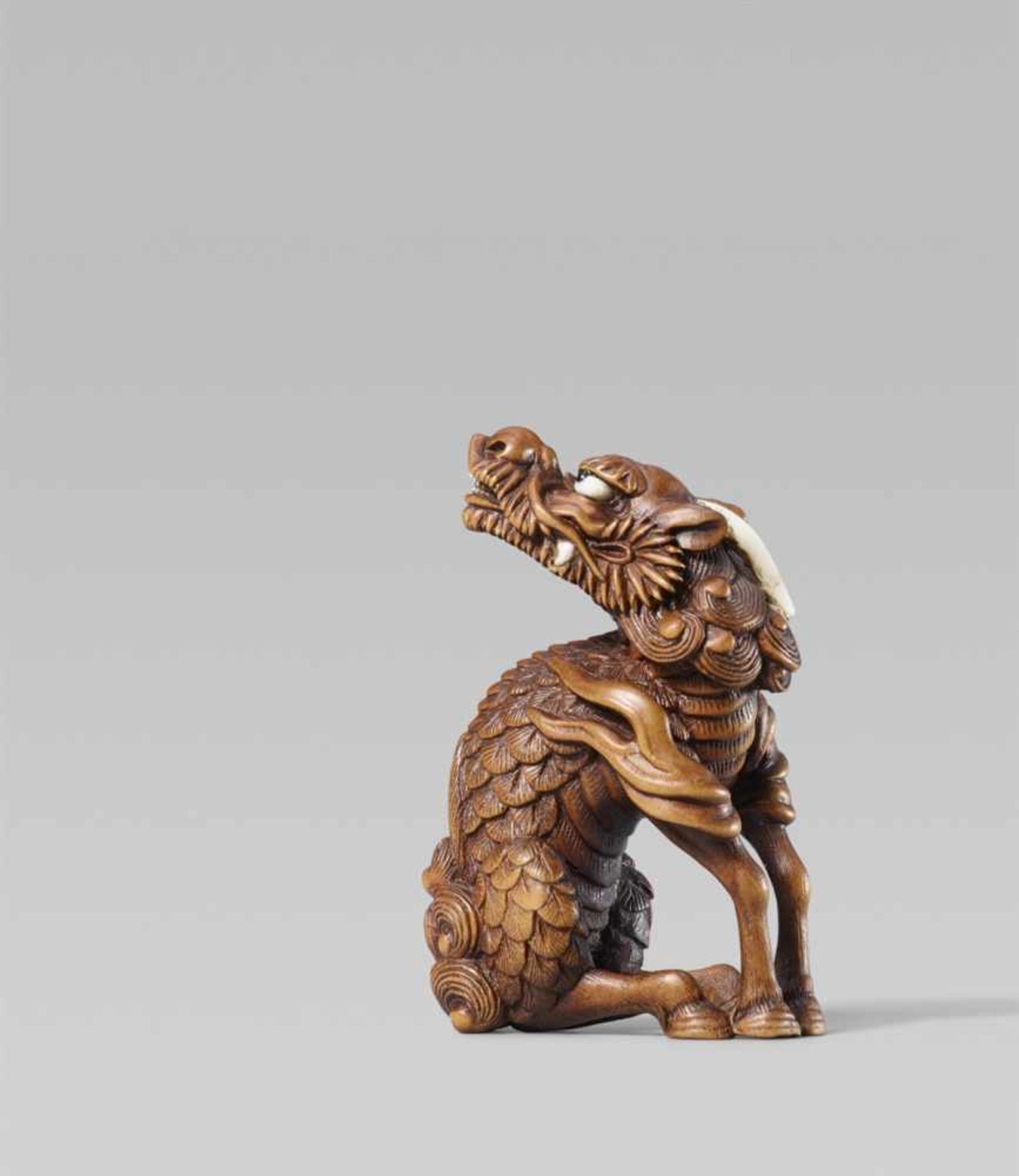 A spectacular boxwood netsuke of a kirin, by Ryûjo. Late 19th centurySeated on its haunches, head