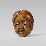 A very large and fine Edo school netsuke of an Okame mask, by Gyokkô. Mid-19th centuryWith typical