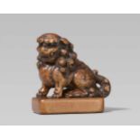 A large wood seal-type netsuke of a shishi. 19th centurySeated with a curly mane and tail on a