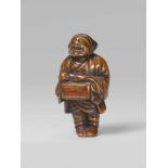 A boxwood netsuke of a street puppeteer. 19th centuryStanding with a wooden box hanging from his