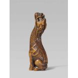 An attractive boxwood netsuke of a kirin. 19th centurySeated on its haunches, howling and raising