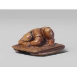 A boxwood netsuke of a sleeping peasant. Mid-19th centuryCrouching on a folded straw mat, the head