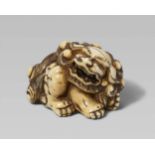 An ivory netsuke of a mighty shishi. Late 18th/early 19th centurySeated, the head turned to the