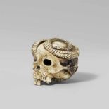 A macabre bone netsuke of a skull and a snake. Late 19th centuryA long slender snake winds through