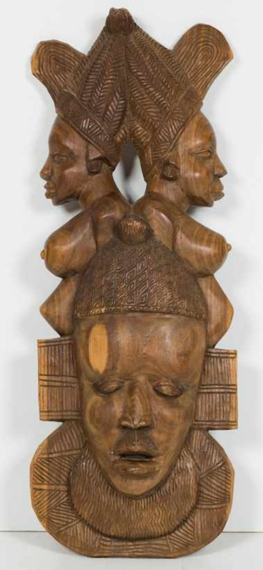 Schnitzerei.Helles Holz. Maskengesicht bekrönt von zwei weiblichen Büsten. H. 86 cm.(54054)