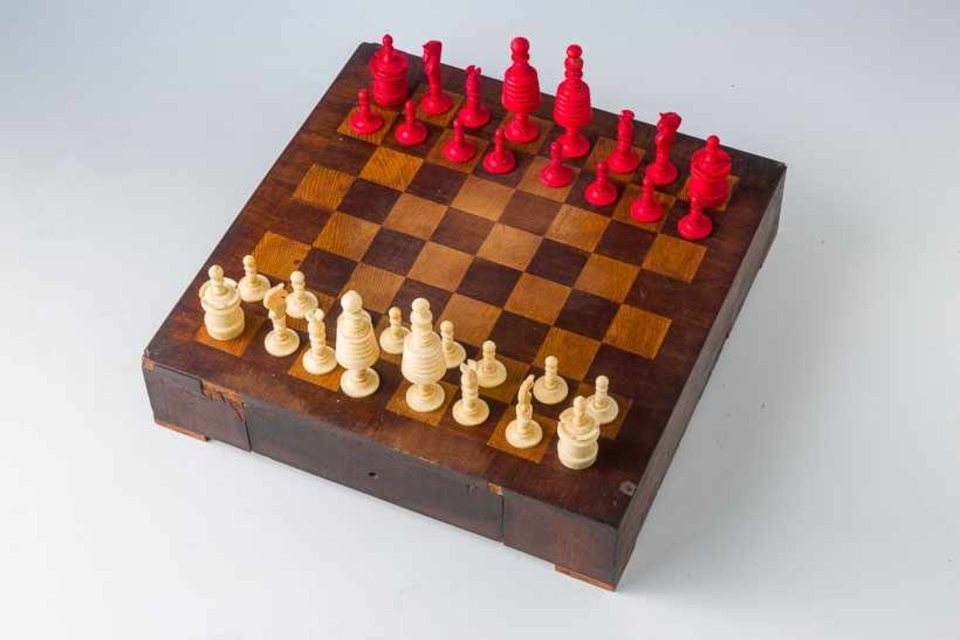Schachspiel mit 32 Beinfiguren,gedrechselt, teils rot eingefärbt. H. 3 bis 9 cm. England, 2. H.