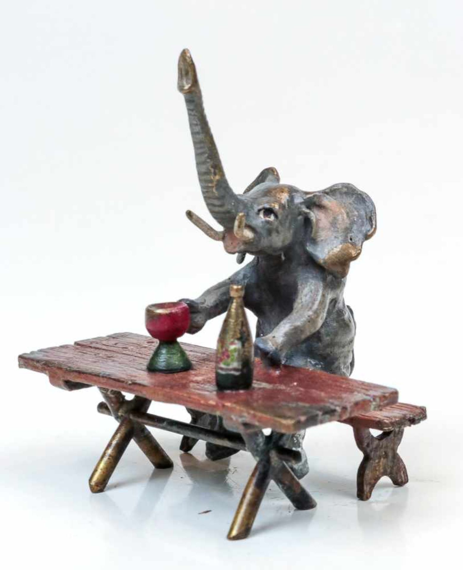 Wiener Bronze Elefant.Auf Holzbank mit Weinglas und Flasche. Naturalistisch bemalt. H. 6,5 cm. Unter
