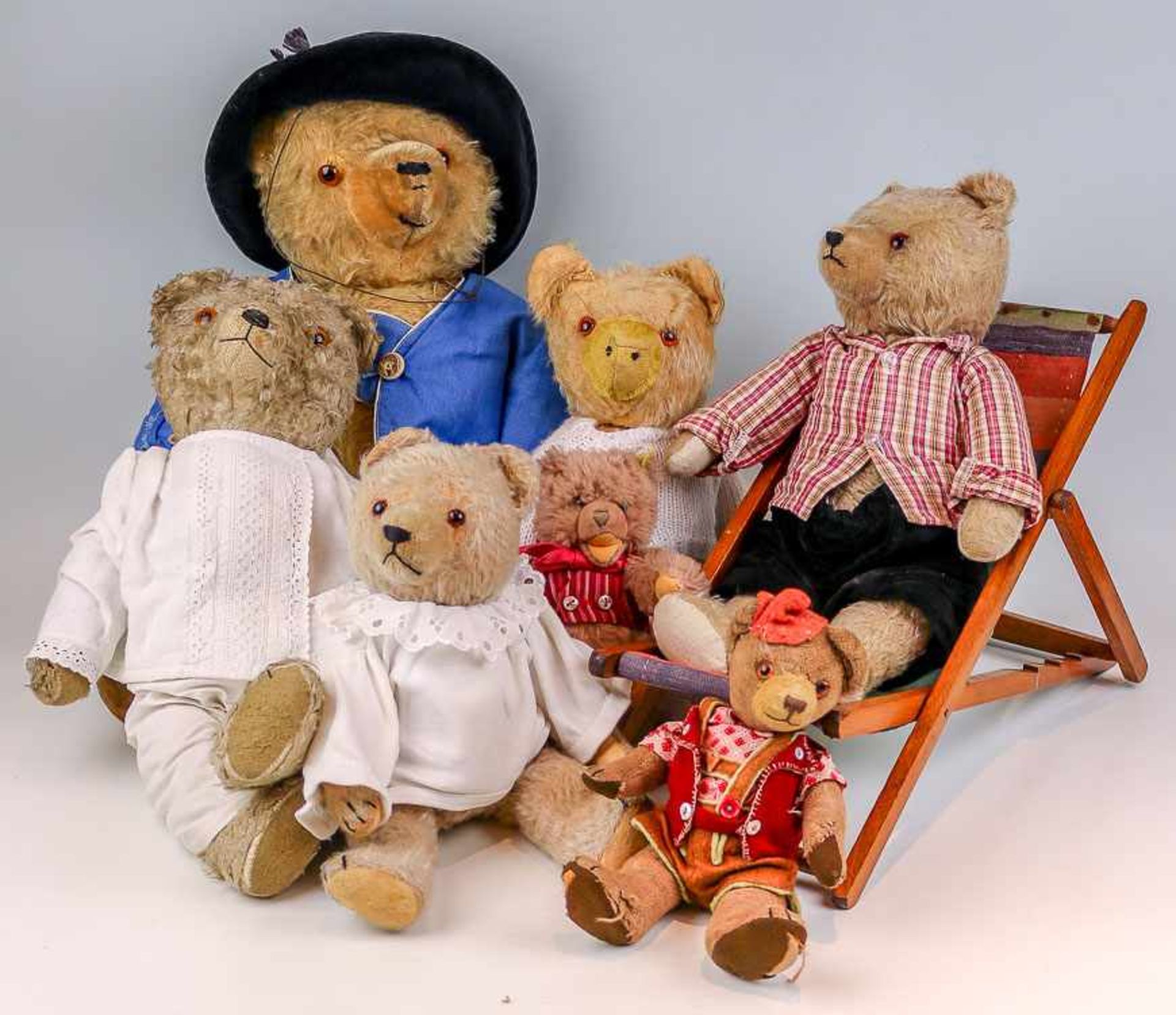 Sammlung von sieben TeddybärenUm ca. 1950/90Bewegliche Köpfe und Glieder. Glasaugen. Bekleidet. (