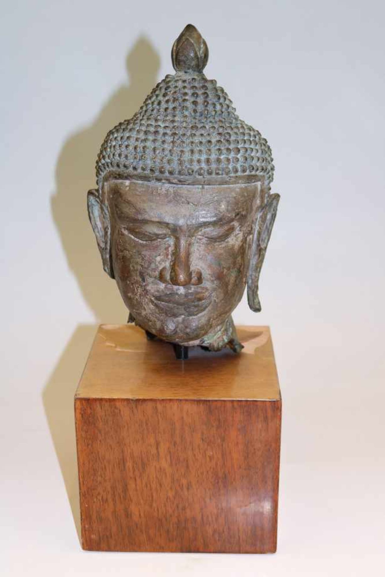 Kopf eines Buddha m. LöckchenfrisurThailandBronze, patiniert. H. 26 cm. Auf rechteckigem