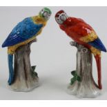 Pair of Sitzendorf porcelain parrots, both sitting on a tree stump, one with hairline crack,