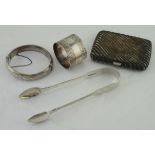 Four silver items, comprising cigarette case, sugar tongs, napkin ring & a bangle, total weight 5.