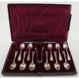 Boxed set of 11 silver spoons (one missing) and a silver pair of sugar tongs. Hallmarked for