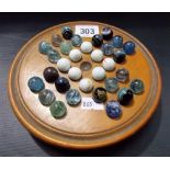 A turned wood marble solitaire board with marbles