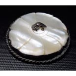 Silver and mother of pearl circular brooch, the centre inset with leaf decoration, possibly by