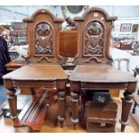 Pair of Victorian oak hall chairs, the arch back with carved and pierced foliate shield, painted