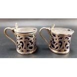 Pair of Edwardian cylindrical scroll pierced hinge lidded mustard pots with scallop shell thumbpiece