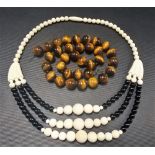 Pre-War ivory and black stone bead necklace; together with a tiger's eye bead necklace (2)