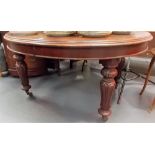 Victorian mahogany oval extending dining table upon carved baluster legs with brass caps and ceramic