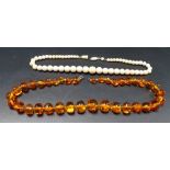 Antique ivory graduated bead necklace; together with an amber style bead necklace (2).