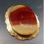 Yellow metal mounted oval banded agate slice brooch, the yellow metal frame foliate scroll engraved,