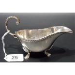George V silver sauce boat with flying scroll handle, gadrooned rim and on triple feet, Birmingham