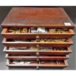 A stained pine five drawer collectors chest containing a quantity of 1920's Meccano cogs, wheels,