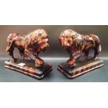 Pair of 19th Century Staffordshire treacle glaze opposing lions, each standing and resting a paw