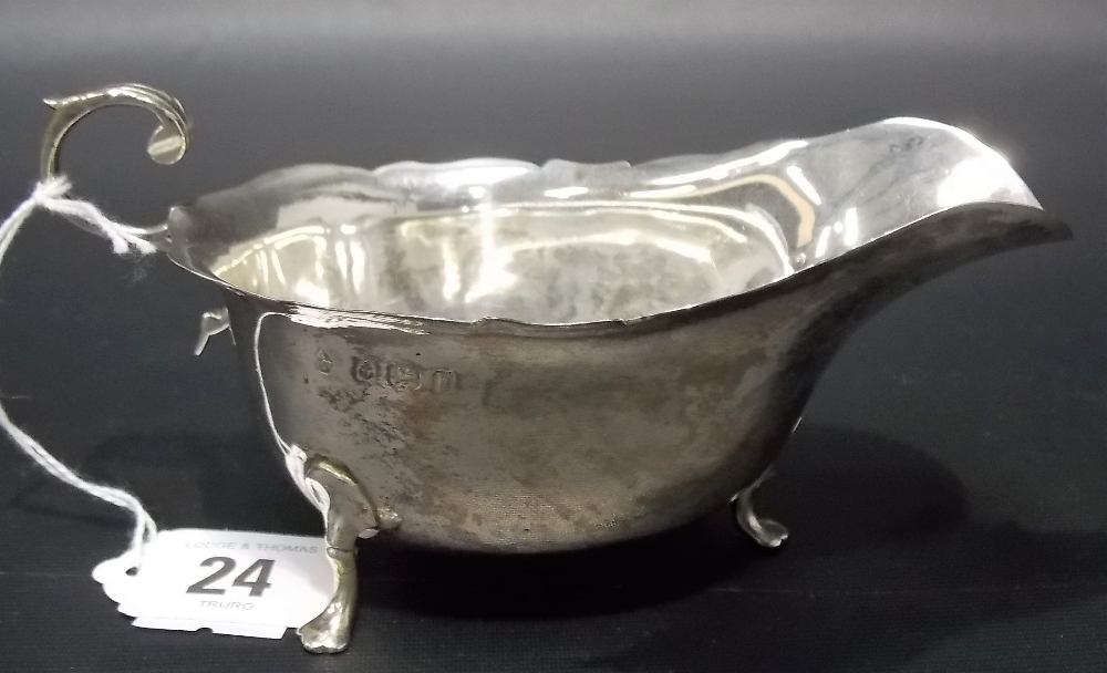 Edwardian silver sauce boat by Asprey London, with flying scroll handle and on triple feet,