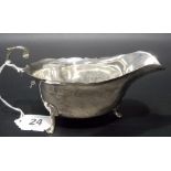 Edwardian silver sauce boat by Asprey London, with flying scroll handle and on triple feet,