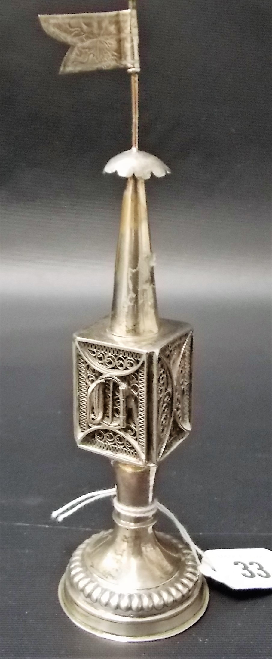 A white metal filigree incense burner with flag surmount.