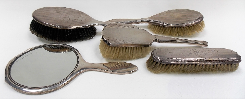 Five silver engine turned dressing table items including a hand mirror.