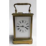 Small brass carriage timepiece with white enamel dial with Roman numerals, the movement striking