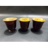 Set of three Chinese lacquer games cups with gilded interiors.