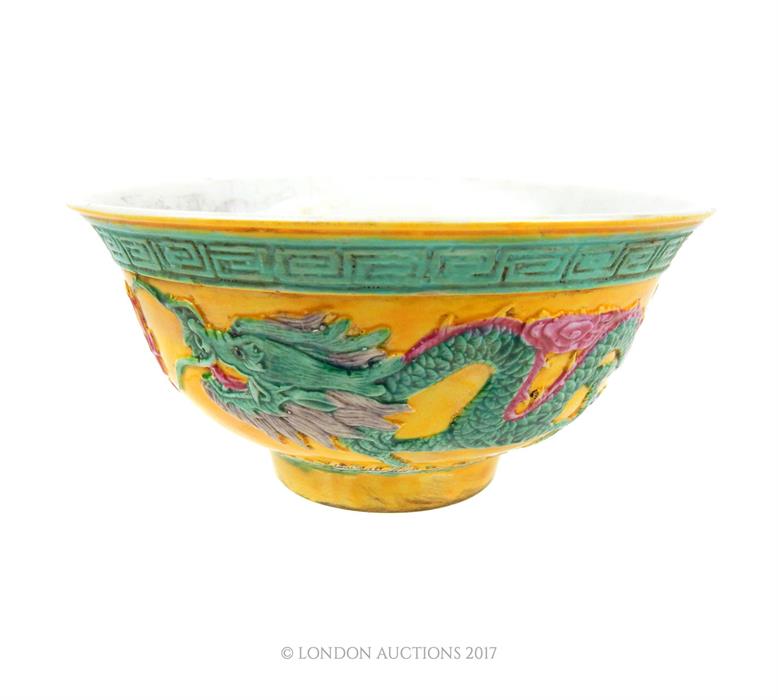 A Chinese porcelain bowl, decorated in relief with dragons