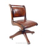 A mahogany swivel desk chair with brown leather upholstery