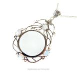 A sterling silver magnifying glass pendant inset with opalites on a silver chain