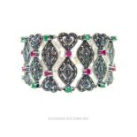 A striking, large, sterling silver, ruby and emerald studded bracelet