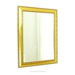 A large, gilt wall mirror with bevelled glass mirror plate