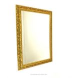 A large, rectangular ornamental wall mirror with moulded, gilt frame