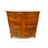 A bow fronted cherry wood chest of four rows of short drawers