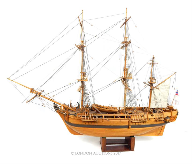 A wooden plank built model of the HMS Bounty with stand; approximately 93cm long overall.