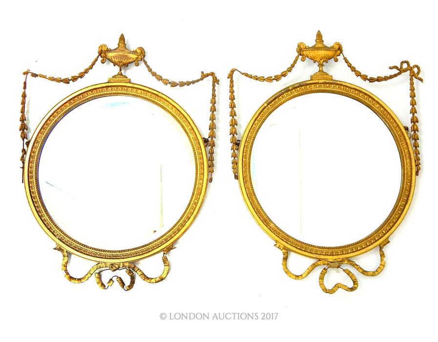 A pair of Edwardian Adams Revival circular bevelled plate mirrors, crested with urns and stags, 66 x